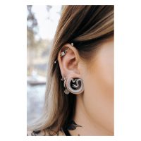 Schwarze Ear Saddles in Schlangenform im Ohr getragen, Piercing im Freien