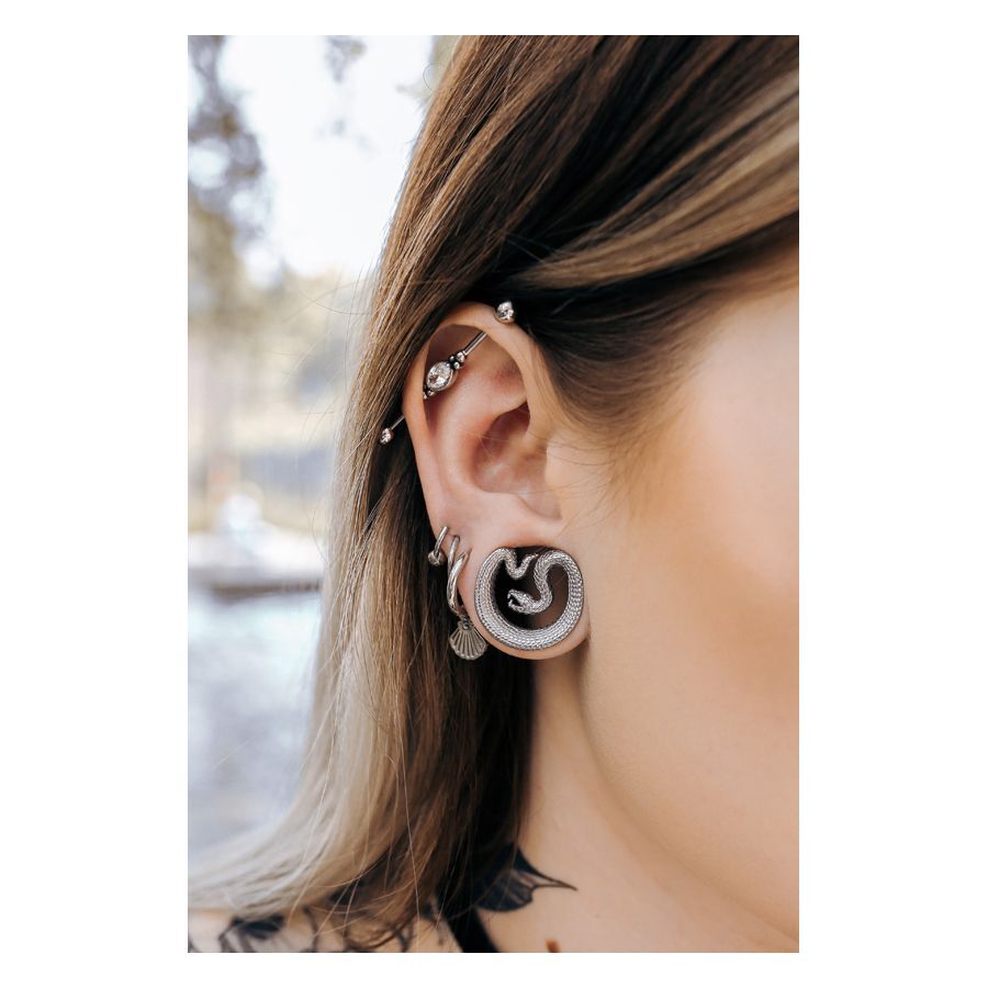 Schwarze Ear Saddles in Schlangenform im Ohr getragen, Piercing im Freien