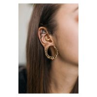 Goldene Blumen Ohrsättel in Ohr mit weiteren Piercings auf neutralem Hintergrund