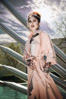 Frau mit silbernen Bat Hoops Ohrringen im sommerlichen Ambiente, rosa Mantel.