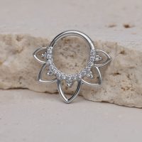 Silberner Septum Clicker mit Blumenmuster und Kristallen auf hellem Stein