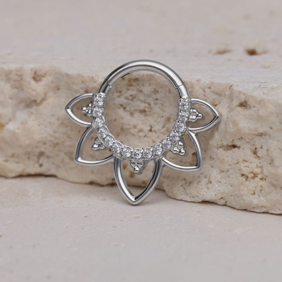 Silberner Septum Clicker mit Blumenmuster und Kristallen auf hellem Stein