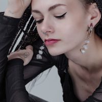 Frau mit Rocks Ohrgewichten aus Silber am Ohr und Nasenpiercing