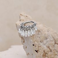 Silberner Piercing-Ring mit klaren Kristallen auf beigem Hintergrund