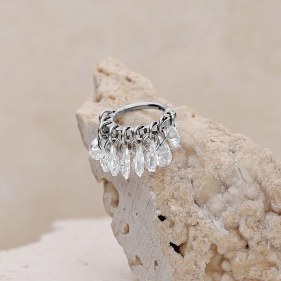 Silberner Piercing-Ring mit klaren Kristallen auf beigem Hintergrund