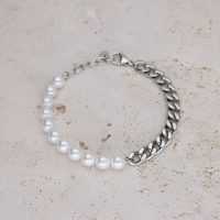 Armband mit weißen Perlen und silberner Kette auf hellem Stein