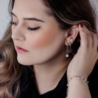 Frau mit eleganten schwarzen und silbernen Chunky Pearl Hoops und anderen Ohrpiercings