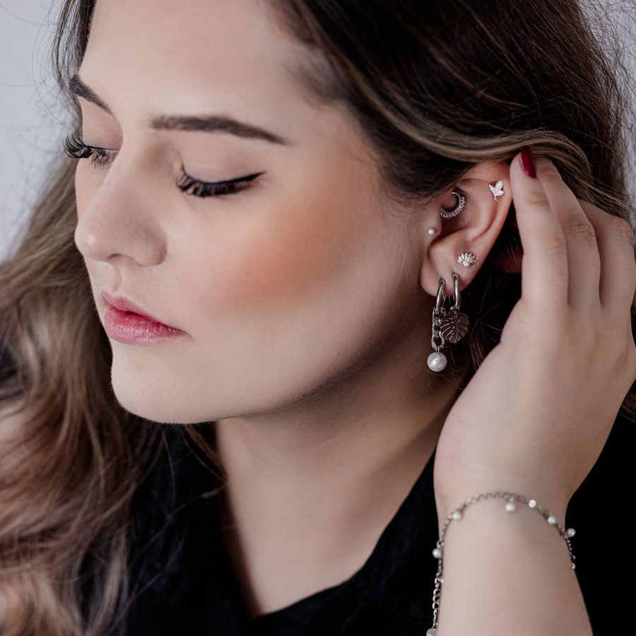Frau mit eleganten schwarzen und silbernen Chunky Pearl Hoops und anderen Ohrpiercings