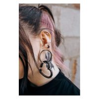 Ohr mit mehreren Piercings, darunter ein schwarzer Luna Earbarbell und ein großer Tunnel, Haarsträhne in Rosa