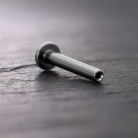 Silbernes Titan Push Fit Labret auf dunklem Holzuntergrund