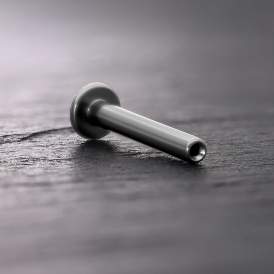 Silbernes Titan Push Fit Labret auf dunklem Holzuntergrund