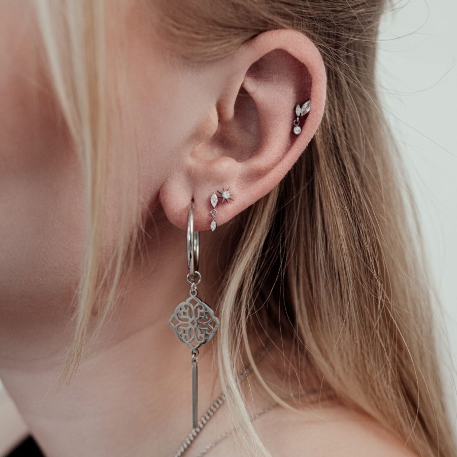 Nahaufnahme eines Ohres mit silbernem Piercing-Aufsatz und klaren Kristallen