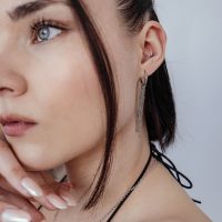 Frau mit Push Fit Blumenaufsatz im Ohr, silberne Kette und Ohrringe, weißer Hintergrund