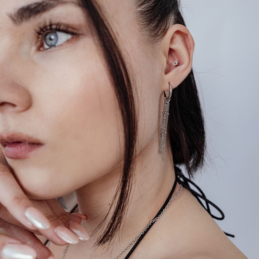Frau mit Push Fit Blumenaufsatz im Ohr, silberne Kette und Ohrringe, weißer Hintergrund