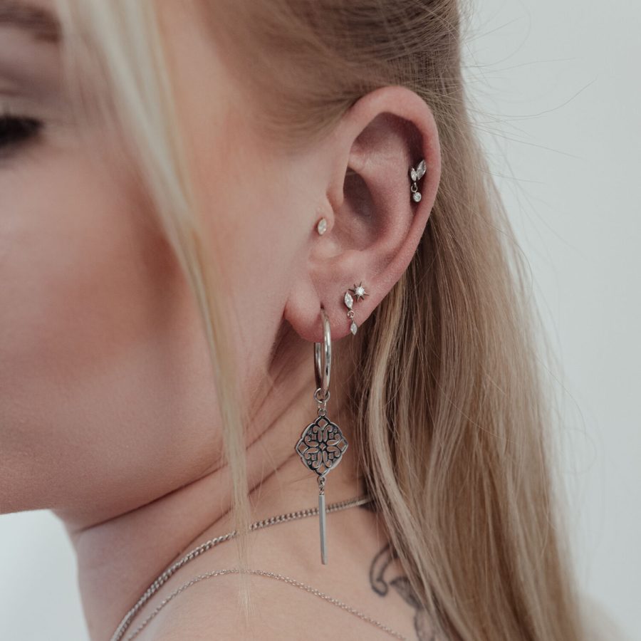Nahaufnahme eines Ohres mit mehreren Piercings, darunter ein großer, silberner Push Fit Kristall Stern Aufsatz.