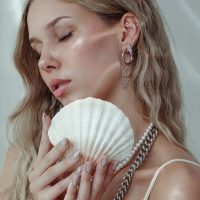 Frau mit Piercing-Aufsatz und Muschel, Ohrringe aus Silber und Gold