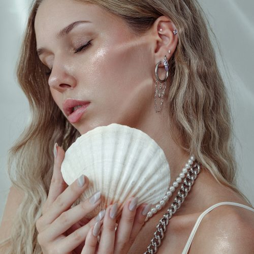 Frau mit Piercing-Aufsatz und Muschel, Ohrringe aus Silber und Gold