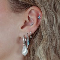 Ohr mit mehreren Piercings, darunter ein silberner Push Fit Aufsatz mit türkisfarbenem Kristall