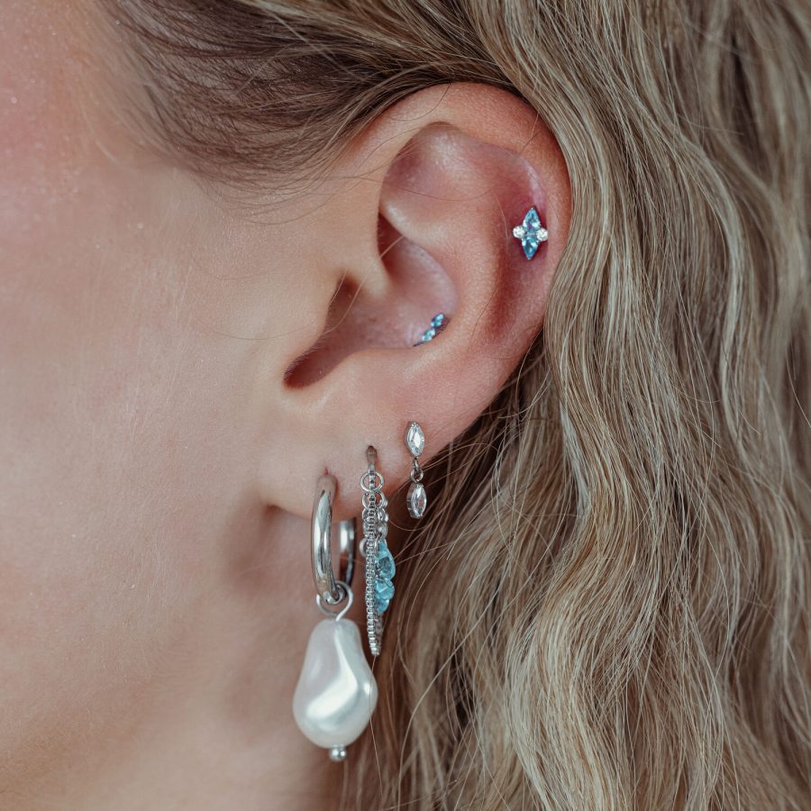 Ohr mit mehreren Piercings, darunter ein silberner Push Fit Aufsatz mit türkisfarbenem Kristall