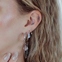 Ohr mit mehreren Piercings, darunter ein silbernes Mystic Dew Aufsatz