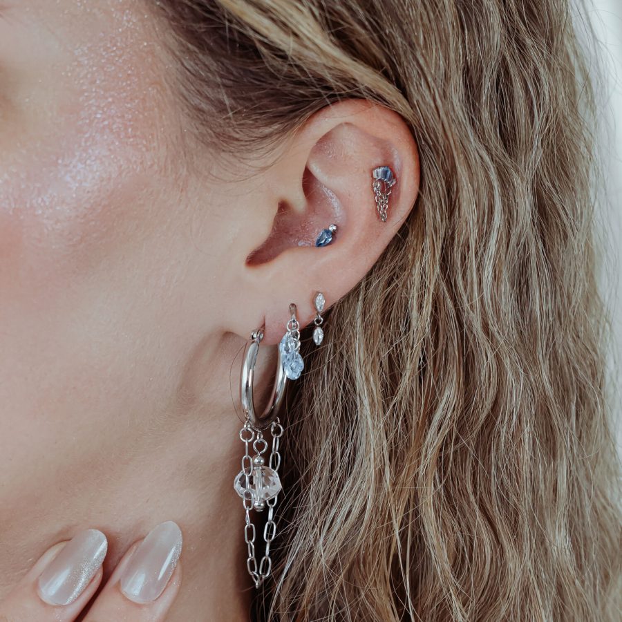Ohr mit mehreren Piercings, darunter ein silbernes Mystic Dew Aufsatz