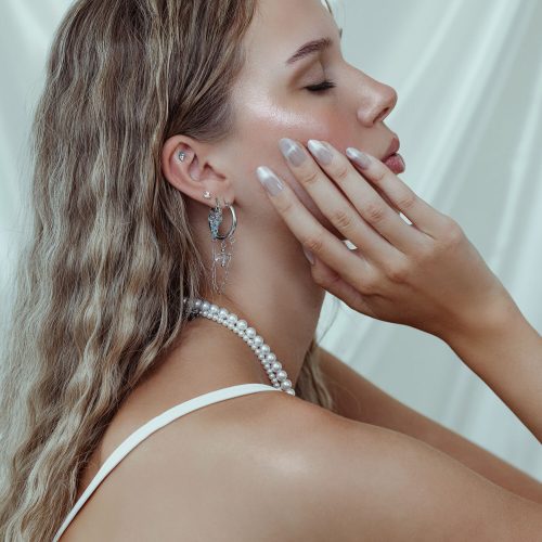 Nahaufnahme eines Ohrrings mit Crystal Reef Aufsatz in Lavendel und Türkis an einem Ohr