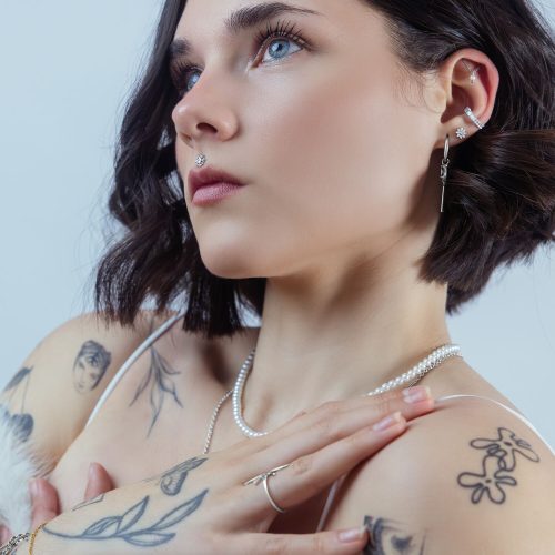 Frau mit mehreren Piercings, Kristallaufsatz im Ohr, stilvoller Look