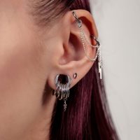 Nahaufnahme eines Ohres mit silbernen Piercingaufsätzen und Ketten