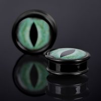 Schwarzer Plug mit grünem Katzenauge-Design auf dunklem Hintergrund