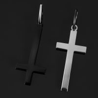 Zwei Kreuz-Ohrringe, einer in glänzendem Schwarz, der andere in Silber, auf schwarzem Hintergrund