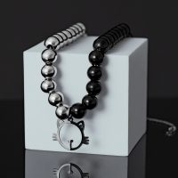 Silber-Schwarze Perlenkette mit Katzenanhänger auf weißem Würfel