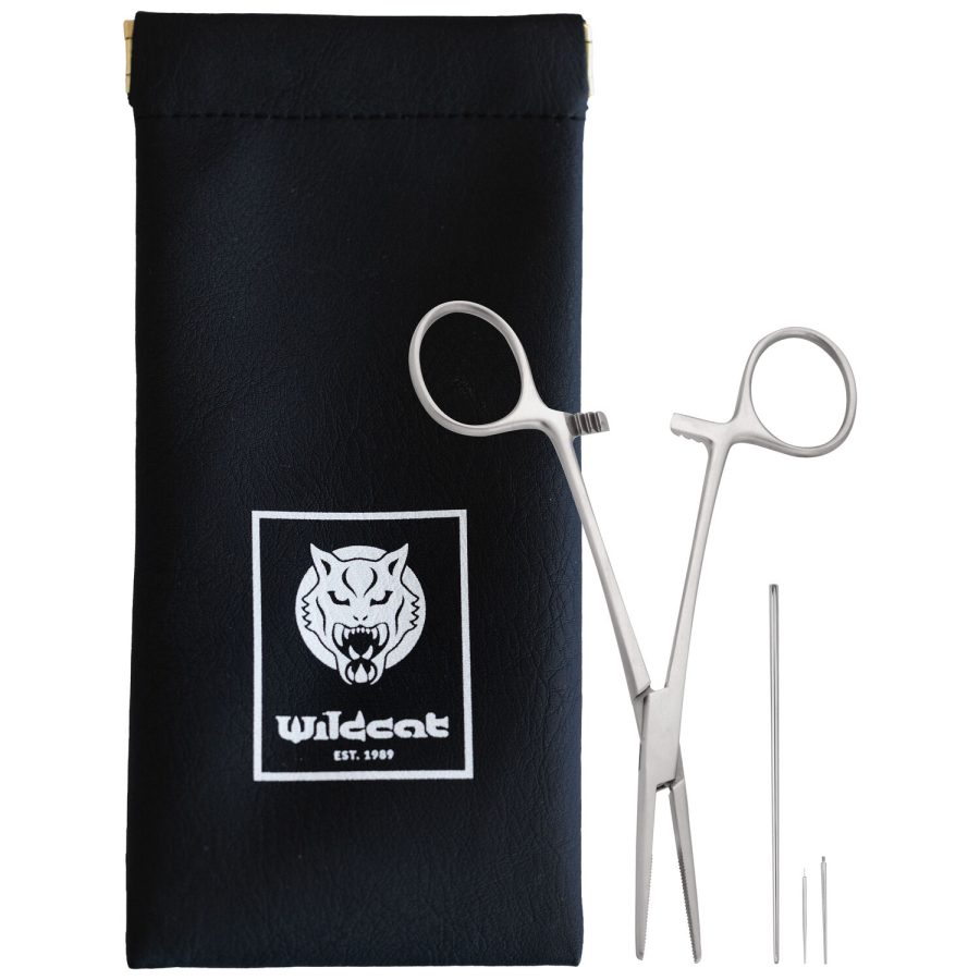 Silberne Piercingzange und Nadeln neben schwarzer Tasche mit Wildcat-Logo