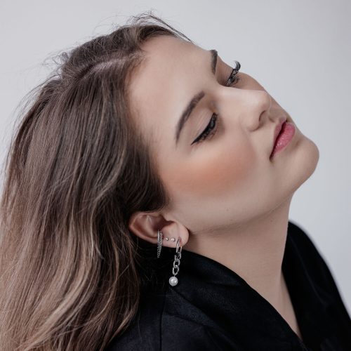 Frau mit Kristall Triple Chain Clicker Piercing im Ohr, auf weißem Hintergrund