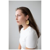 Frau mit goldenen Moonshine Hoops Ohrringen vor grauem Hintergrund