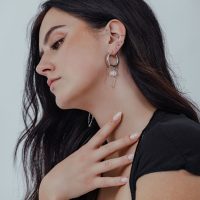 Frau mit langen dunklen Haaren trägt weiße Stone Hoops aus Chirurgenstahl am Ohr