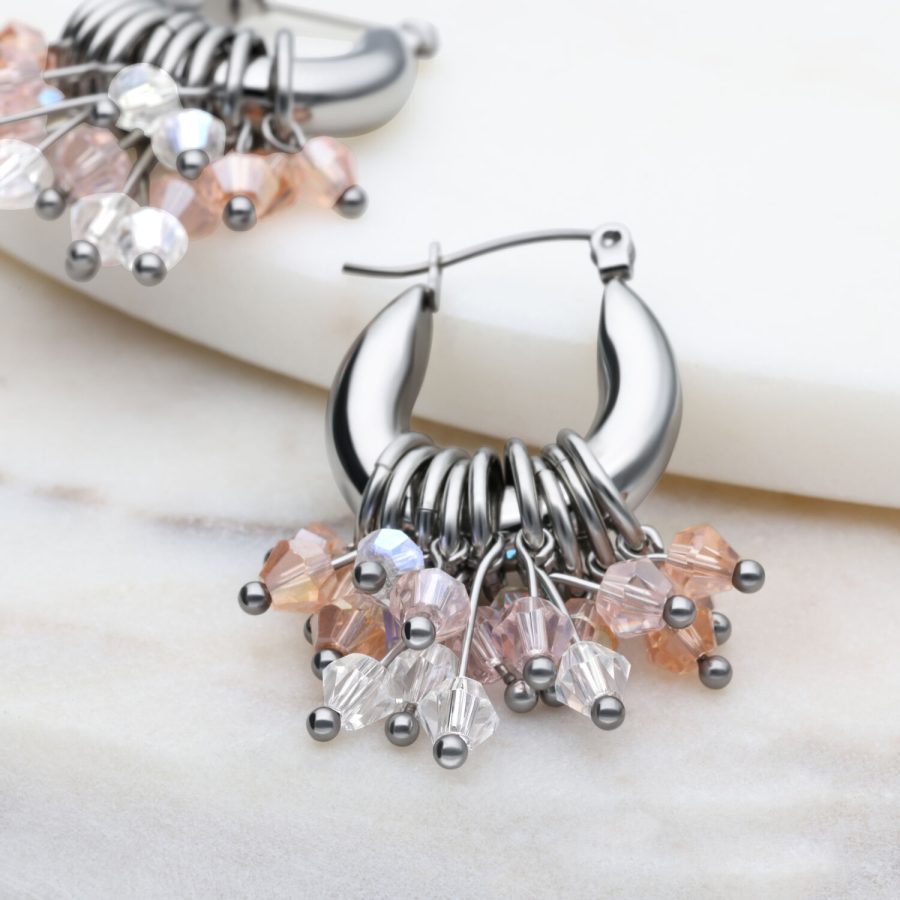 Silberne Glamour Hoops Ohrringe mit bunten Kristallen auf marmoriertem Hintergrund