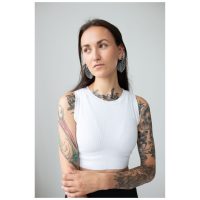 Frau mit tätowierten Armen trägt Monstera Leaf Hoops Ohrringe, weißes Top