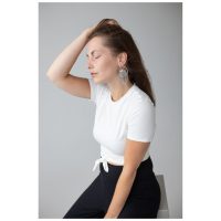 Frau mit weißen T-Shirt trägt elegante silberne La Fleur Ohrringe auf grauem Hintergrund