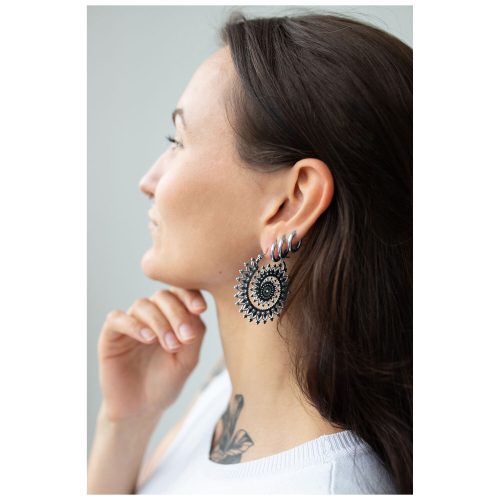 Frau mit silbernen und goldenen Floral Nautilus Hoops vor neutralem Hintergrund
