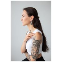 Frau mit Magnolia Hoops Ohrringen, Edelstahl in Schwarz auf grauem Hintergrund