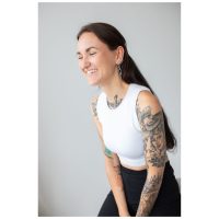 Frau mit langen Haaren und Tattoos trägt Thunderbolt Hoops Ohrringe, weißes Top