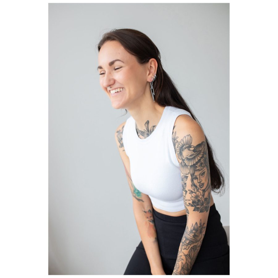 Frau mit langen Haaren und Tattoos trägt Thunderbolt Hoops Ohrringe, weißes Top