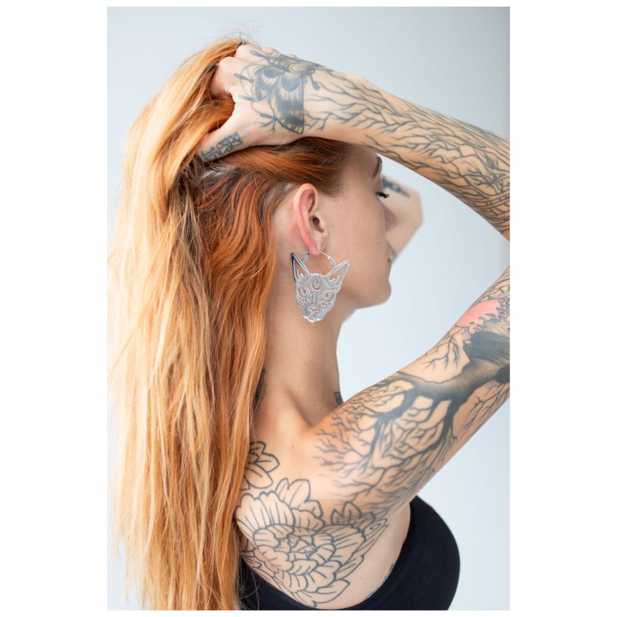 Frau mit roten Haaren trägt silberne Sphynx Hoops vor hellem Hintergrund