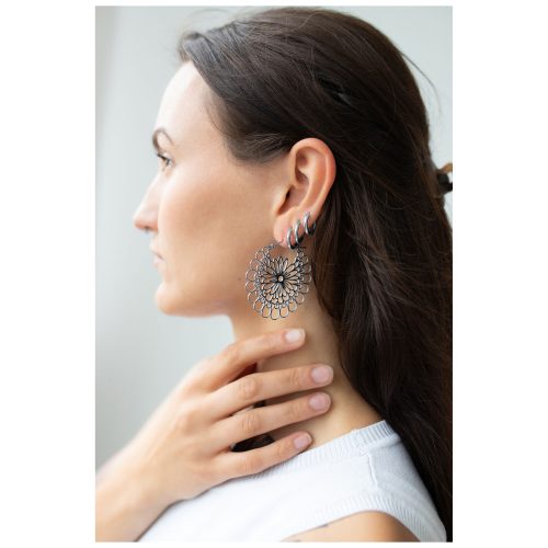 Frau mit Daisy Hoops Ohrringen aus schwarzem und silbernem Chirurgenstahl.
