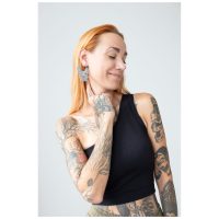 Frau mit Tattoos trägt große Bulldog Hoops Ohrringe