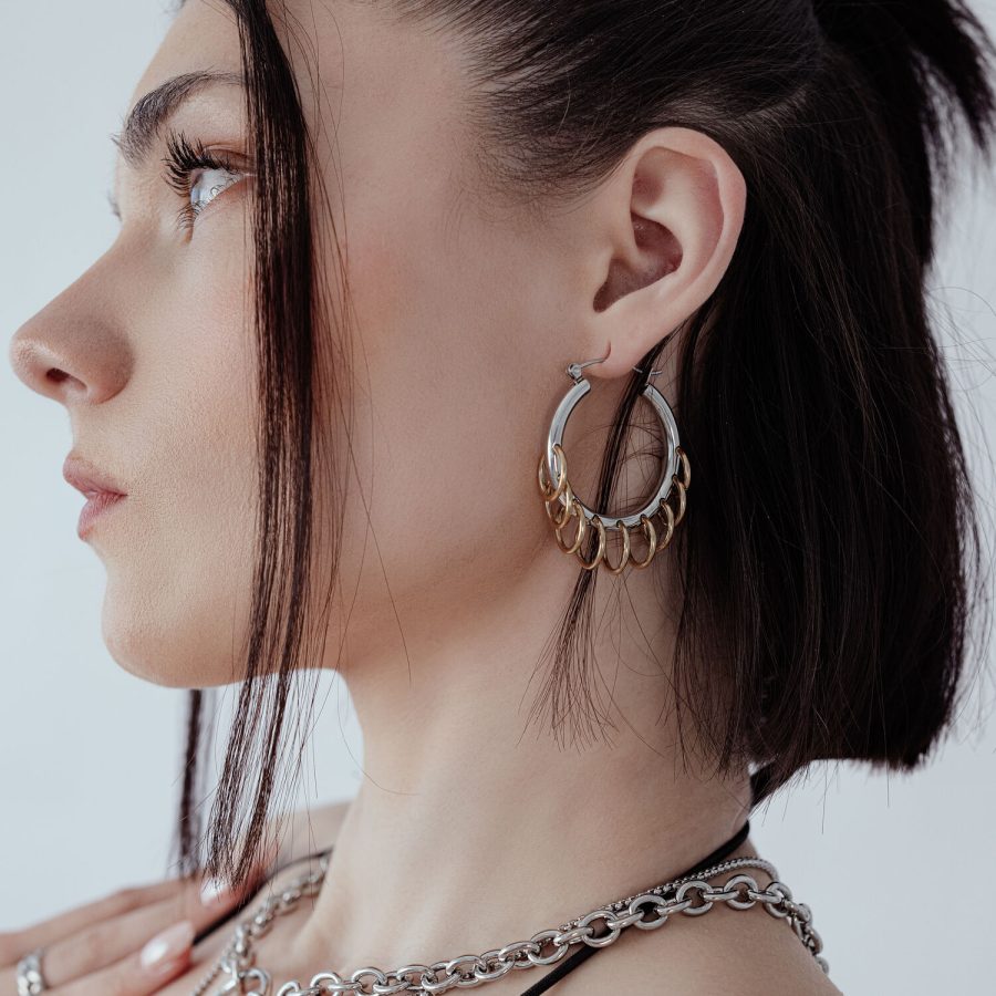 Frau mit stilvollen, massiven Hoops mit Loops in Silber und Gold vor weißem Hintergrund