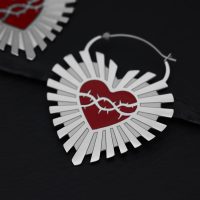 Silberne Creolen in Herzform mit rotem Dornenkranz auf schwarzem Hintergrund