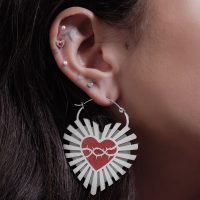 Silberne Ohrringe in Herzform mit Stacheldrahtmotiv an einem Ohr