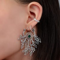 Nahaufnahme eines Ohres mit silbernem Ohrhänger in Blumenform und kleinem Stecker