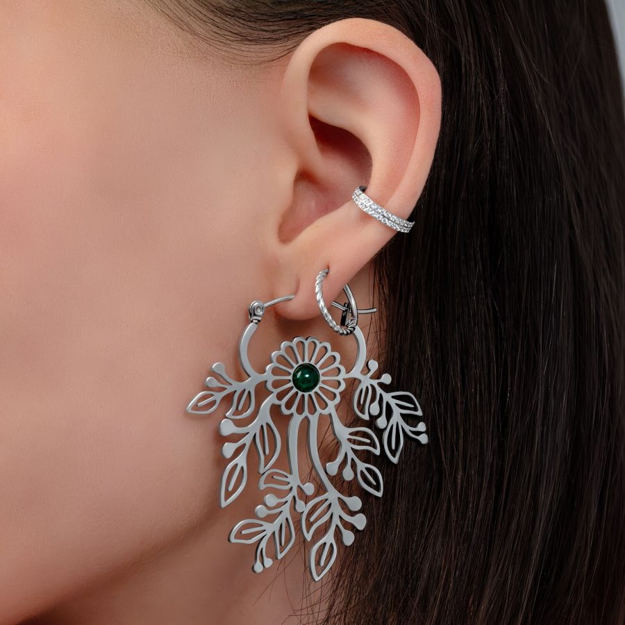 Nahaufnahme eines Ohres mit silbernem Ohrhänger in Blumenform und kleinem Stecker